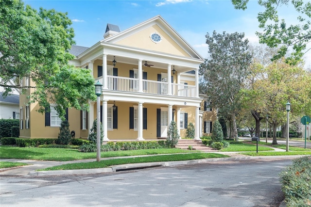 greek revival inspired property featuring a balcony and a front lawn