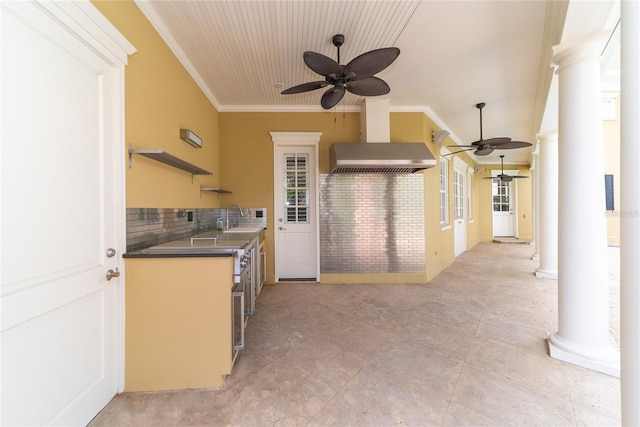 kitchen with crown molding, backsplash, ceiling fan, decorative columns, and wall chimney exhaust hood