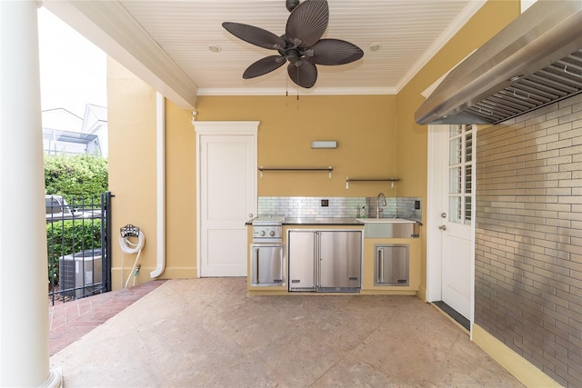 kitchen with wall chimney range hood, ceiling fan, crown molding, backsplash, and sink