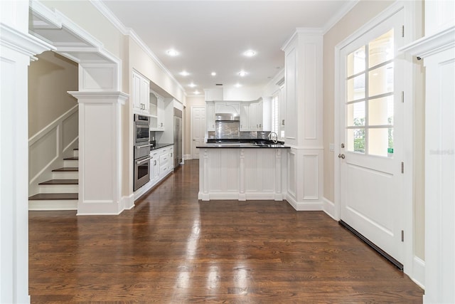 kitchen with backsplash, crown molding, white cabinets, and dark wood-type flooring