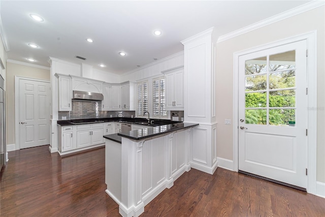 kitchen with kitchen peninsula, white cabinetry, dark hardwood / wood-style floors, and wall chimney range hood