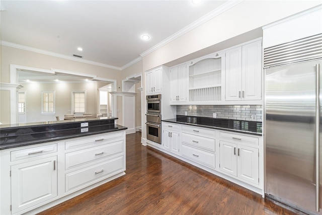 kitchen with dark hardwood / wood-style floors, ornamental molding, appliances with stainless steel finishes, tasteful backsplash, and white cabinetry