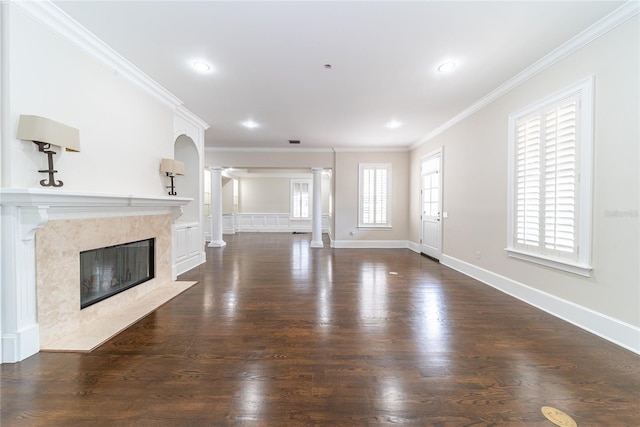 unfurnished living room featuring a high end fireplace, crown molding, dark hardwood / wood-style flooring, and decorative columns