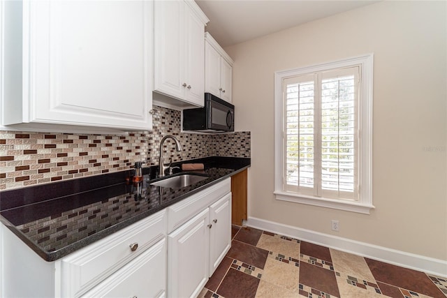 kitchen featuring tasteful backsplash, white cabinetry, dark tile floors, dark stone countertops, and sink