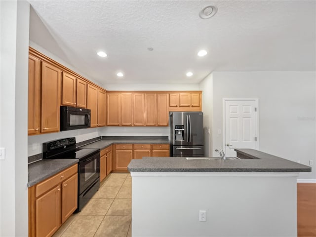 kitchen with an island with sink, light tile floors, a textured ceiling, black appliances, and sink