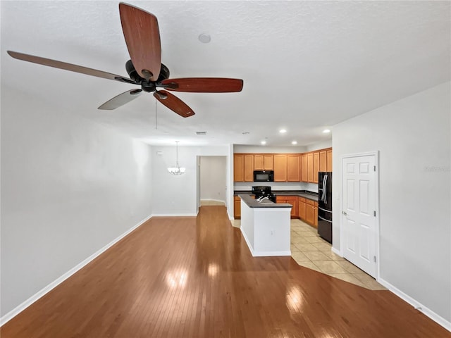 kitchen featuring a center island, light tile flooring, ceiling fan with notable chandelier, and black appliances