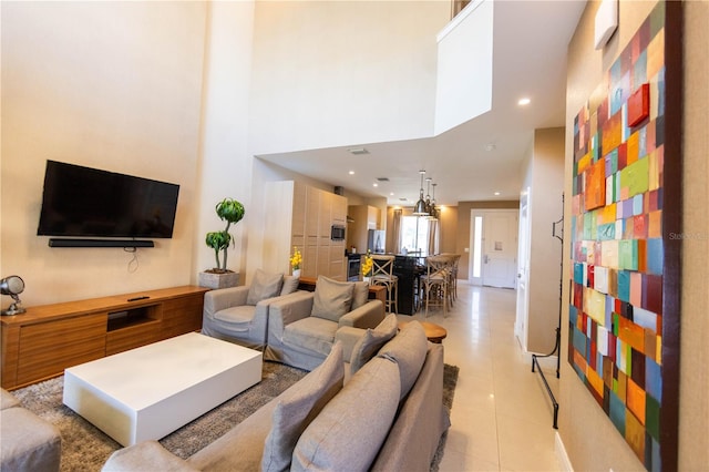 living room with a towering ceiling and light tile floors