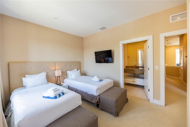 bedroom featuring ensuite bath and light carpet