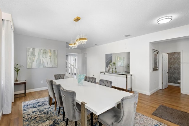 dining room featuring light wood-type flooring and an inviting chandelier