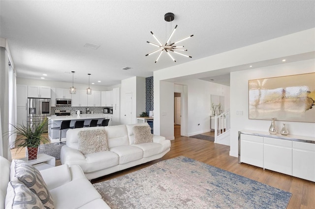 living room featuring wood-type flooring, a notable chandelier, and a textured ceiling