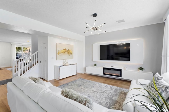 living room featuring a chandelier, light hardwood / wood-style flooring, and a textured ceiling