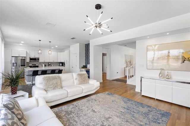 living room with a textured ceiling, hardwood / wood-style flooring, and a chandelier