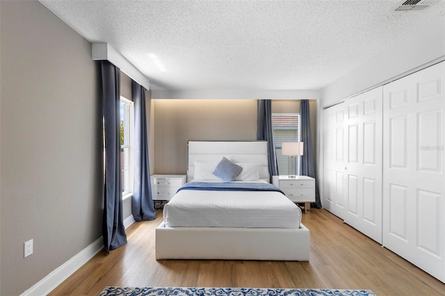 bedroom featuring a closet, light hardwood / wood-style flooring, and a textured ceiling