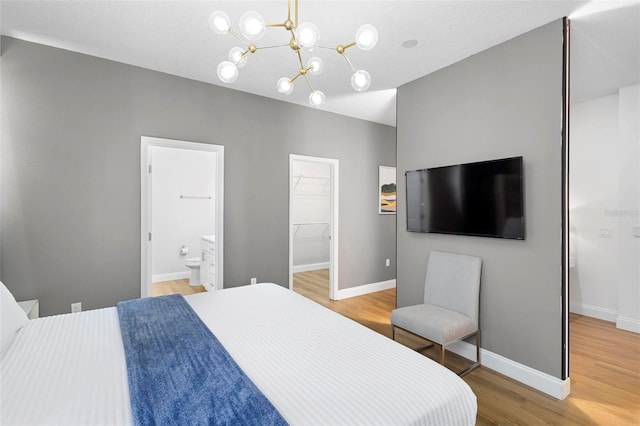 bedroom featuring a closet, a spacious closet, ensuite bath, and light hardwood / wood-style floors