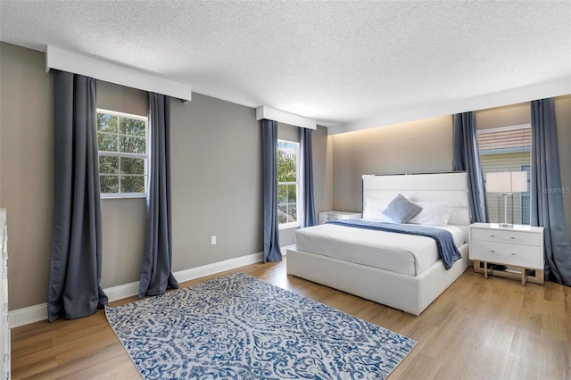 bedroom featuring wood-type flooring, a textured ceiling, and multiple windows