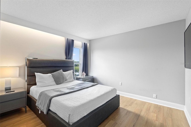 bedroom with a textured ceiling and light hardwood / wood-style floors