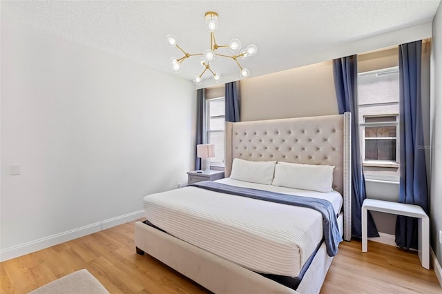 bedroom featuring a notable chandelier, light hardwood / wood-style floors, and a textured ceiling