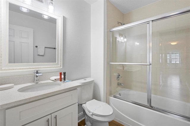 full bathroom featuring hardwood / wood-style floors, vanity with extensive cabinet space, toilet, and combined bath / shower with glass door