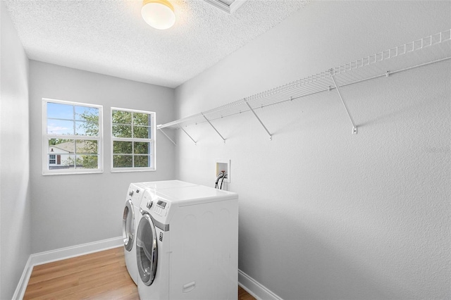 laundry room with washer and clothes dryer, light hardwood / wood-style floors, washer hookup, and a textured ceiling