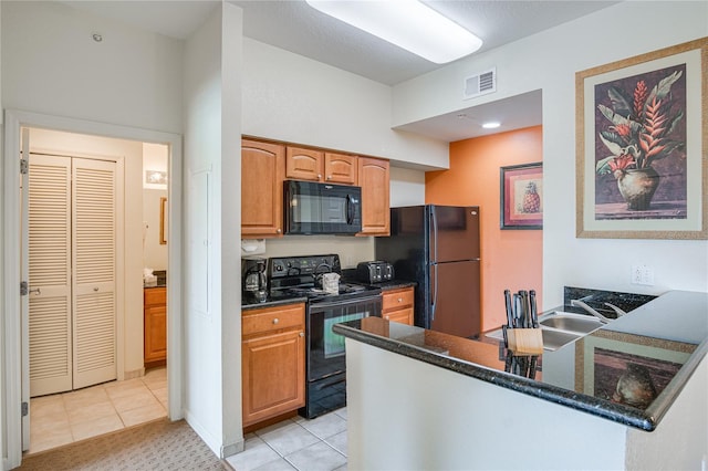 kitchen featuring light tile floors, dark stone countertops, and black appliances