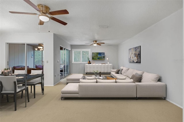 living room with a textured ceiling, light colored carpet, and ceiling fan