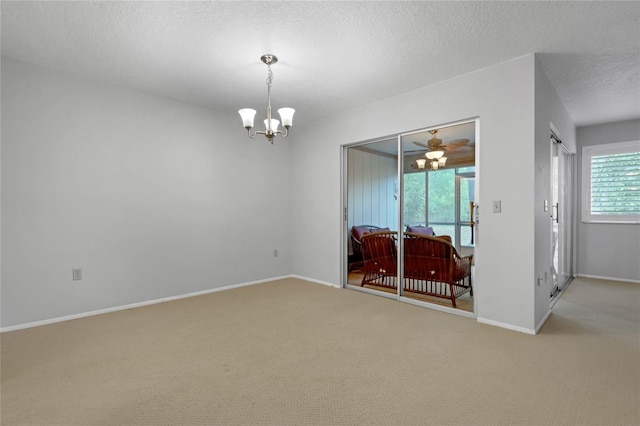 carpeted empty room featuring a textured ceiling and an inviting chandelier