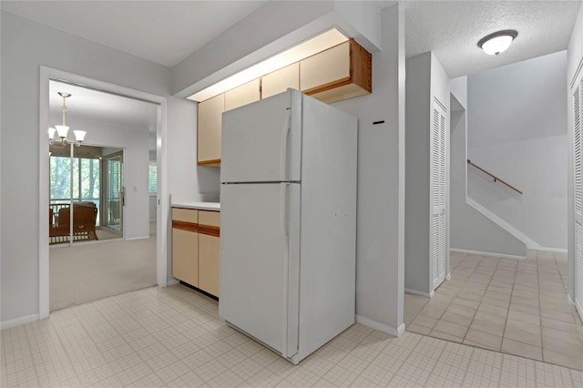 kitchen featuring a textured ceiling, an inviting chandelier, and white refrigerator