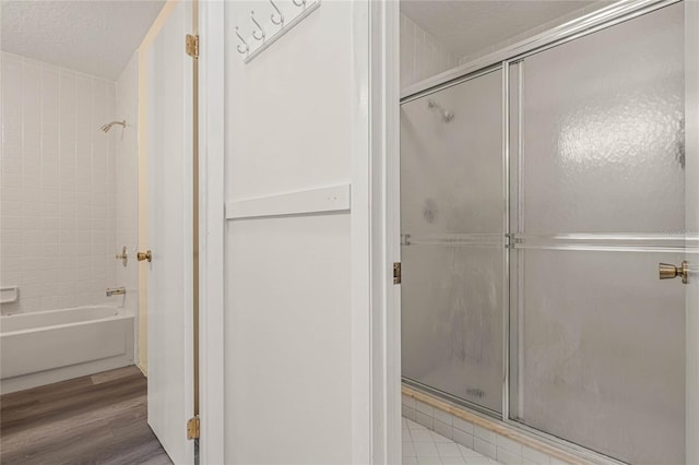 bathroom with a textured ceiling, hardwood / wood-style flooring, and plus walk in shower