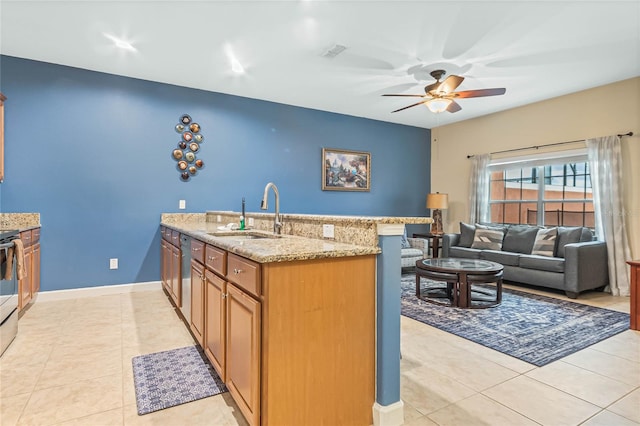 kitchen with light stone counters, ceiling fan, sink, and light tile flooring