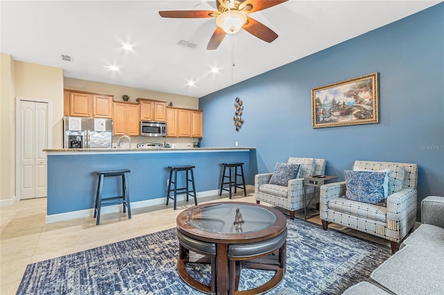 living room featuring ceiling fan, light tile floors, and sink