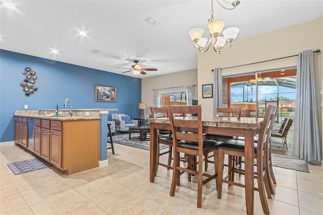 tiled dining area with sink and ceiling fan with notable chandelier