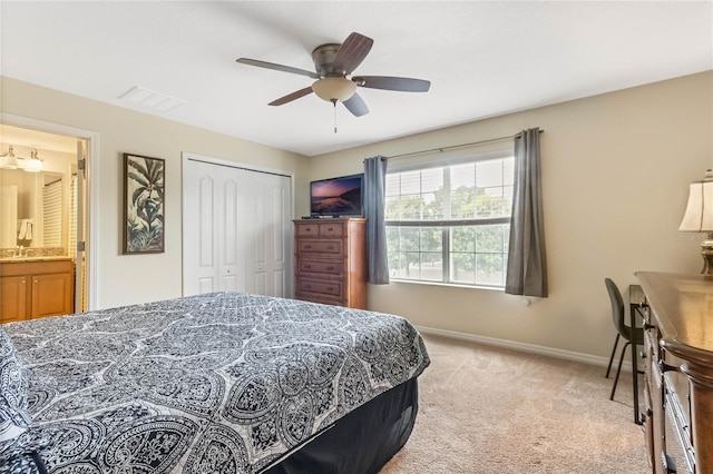 bedroom featuring a closet, ceiling fan, connected bathroom, sink, and light carpet