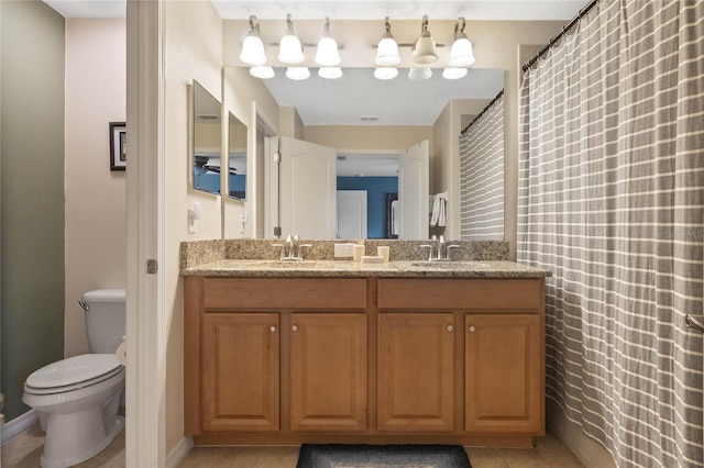 bathroom with tile floors, dual sinks, toilet, and large vanity