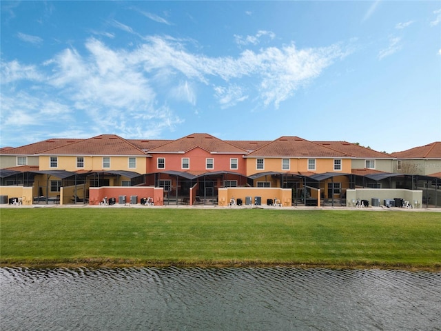 back of property with a lawn and a water view