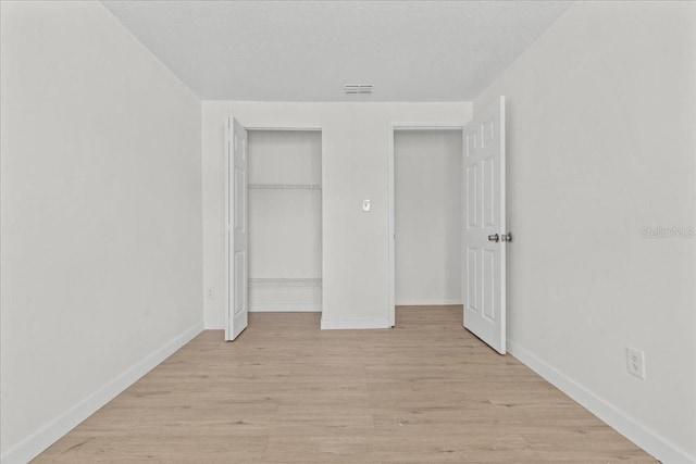 unfurnished bedroom with a textured ceiling, light wood-type flooring, and a closet