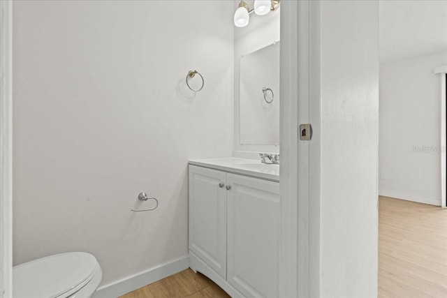 bathroom with vanity, wood-type flooring, and toilet