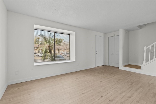 empty room with a textured ceiling and light hardwood / wood-style floors