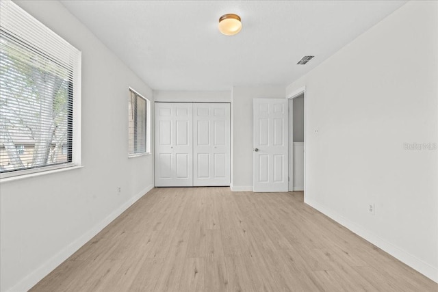 unfurnished bedroom with a closet and light wood-type flooring