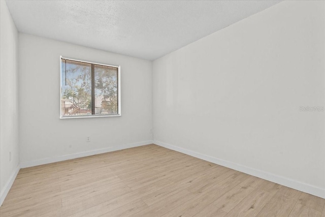 empty room with light hardwood / wood-style flooring and a textured ceiling