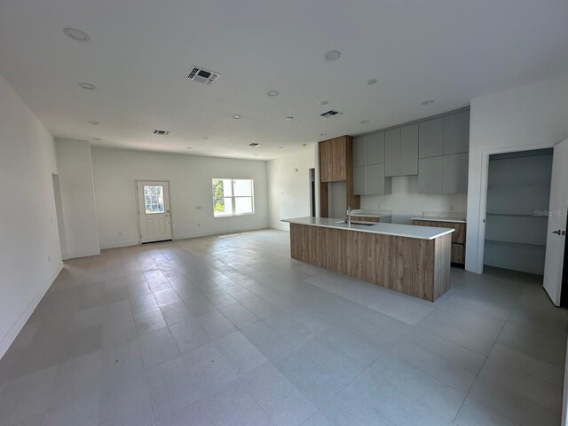 kitchen featuring sink, a center island with sink, and light tile patterned floors