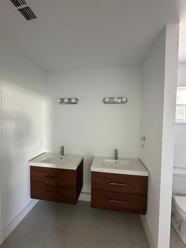 bathroom with tile patterned flooring, toilet, and double vanity