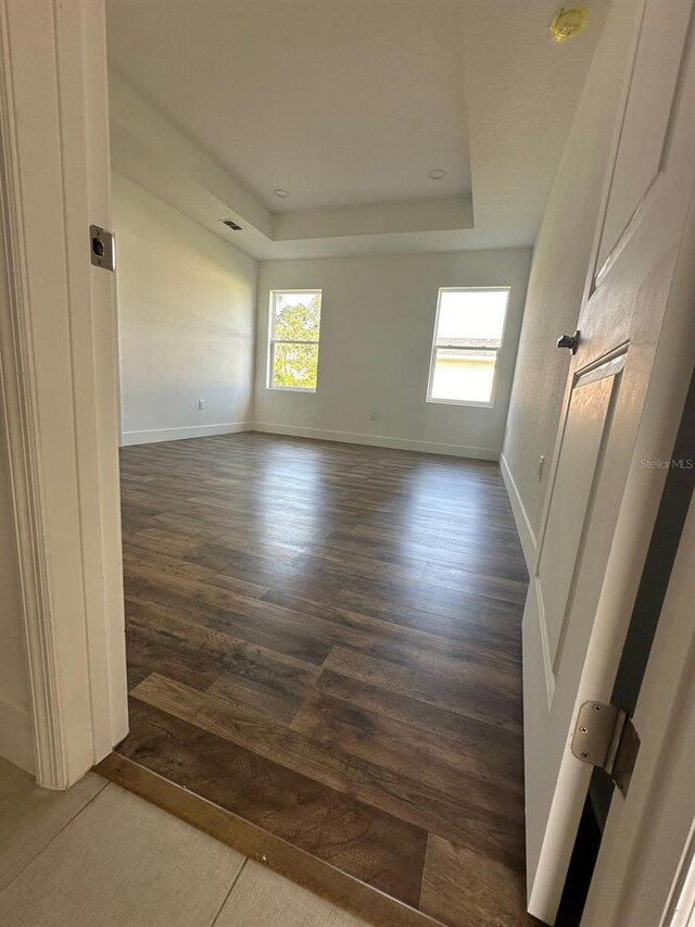 unfurnished room with hardwood / wood-style flooring and a tray ceiling