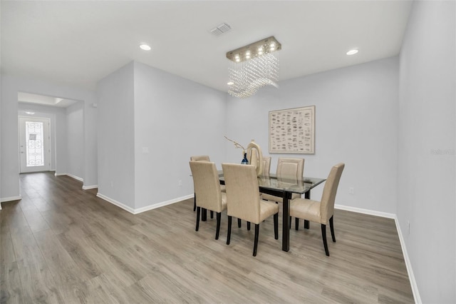 dining room with light wood-type flooring and a chandelier