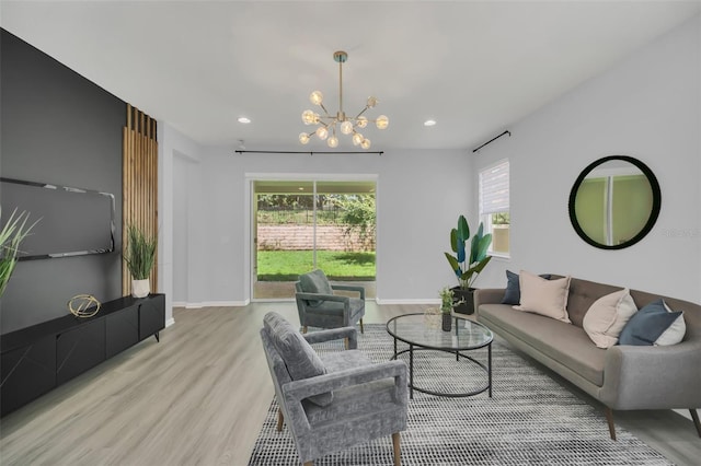 living room with a wealth of natural light, light hardwood / wood-style flooring, and a notable chandelier