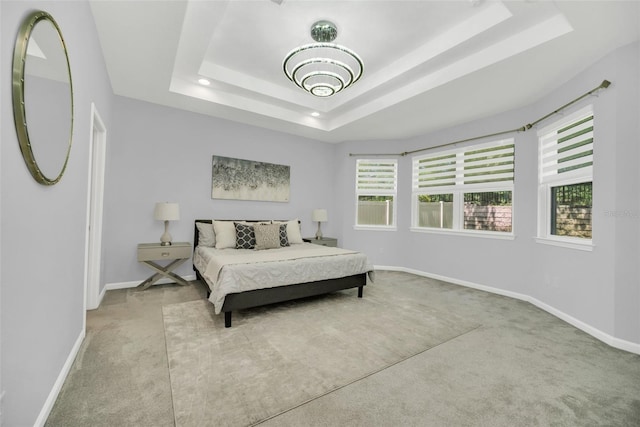 bedroom featuring a tray ceiling, an inviting chandelier, and light carpet