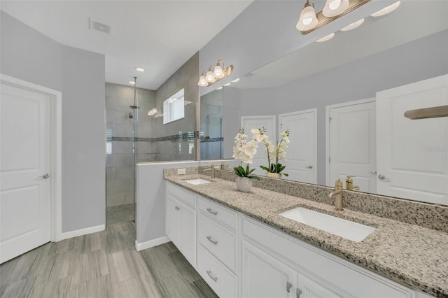 bathroom with tiled shower and vanity