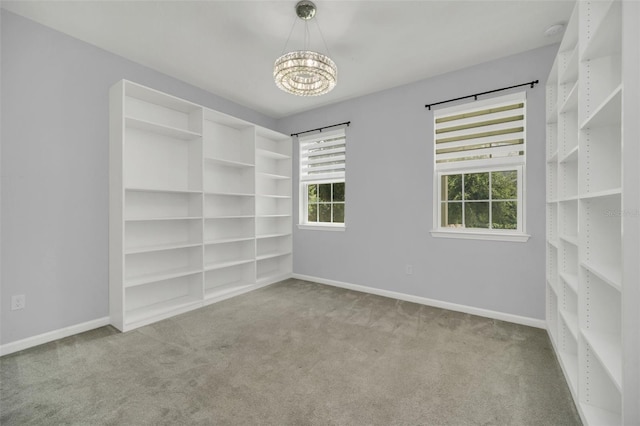 empty room with carpet flooring and an inviting chandelier