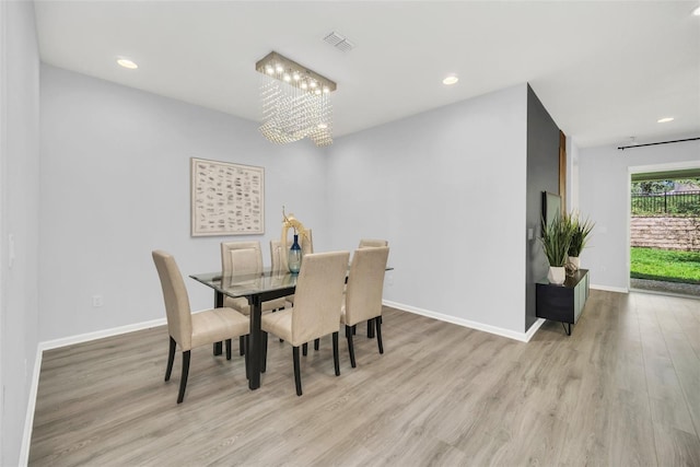 dining room with light hardwood / wood-style flooring and a notable chandelier