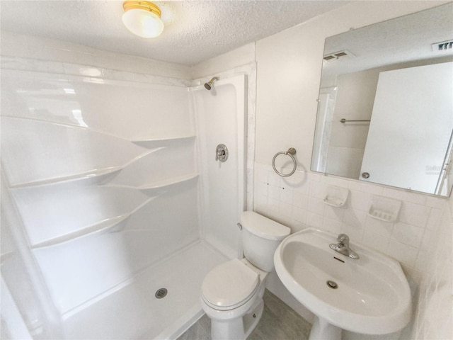 bathroom with tile walls, walk in shower, toilet, sink, and tasteful backsplash