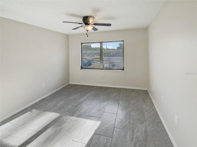 tiled empty room featuring ceiling fan